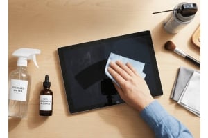 Hand cleaning a tablet screen with a microfiber cloth using isopropyl alcohol and distilled water for safe, streak-free tablet maintenance.